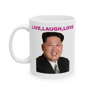 Op de afbeelding: Witte keramische koffiemok met een afbeelding van een man in pak en de tekst "LIVE, LAUGH, LOVE" in roze.