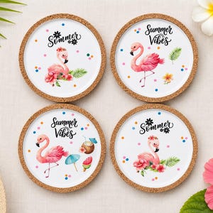 Könnte beinhalten: Ein Set aus vier runden Untersetzern mit Korkrand und weißer Oberfläche. Jeder zeigt eine Illustration eines rosa Flamingos, bunte Punkte und den Schriftzug "Sommer" oder "Summer Vibes" in schwarzer Schrift, ergänzt durch tropische Blumen.