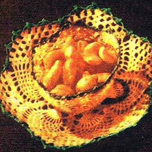 May include: A crocheted doily with a delicate pattern in shades of yellow and brown. The doily is edged with a green trim.