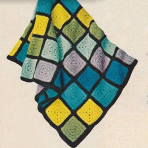 Peut inclure: Une couverture au crochet avec un motif de vitrail dans des tons de bleu, vert, jaune et violet. Les carrés sont soulignés de noir.