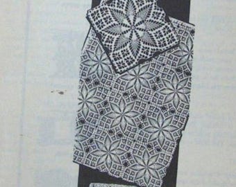 May include: A black and white crocheted doily and tablecloth set. The doily is square with a central starburst design. The tablecloth features a repeating floral pattern. The items are displayed on a black background.