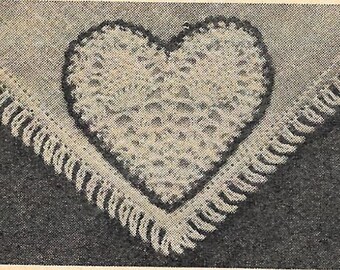 May include: A white crocheted heart with a fringe border on a dark background.