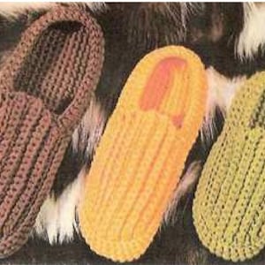 May include: Three crocheted slippers in brown, orange, and green. The slippers are made with a simple stitch pattern and have a rounded toe.