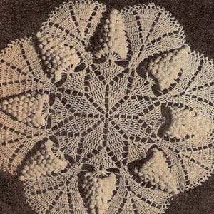 May include: A delicate crocheted doily with a circular design featuring intricate floral motifs. The doily is made with white thread and has a lacy, openwork pattern.