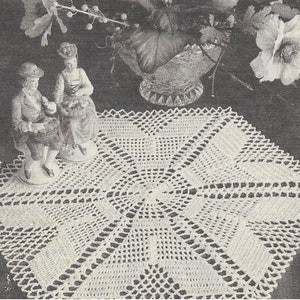 May include: A white crocheted doily with a square shape and a delicate, intricate design. The doily is centered on a dark background and features a raised, textured center.