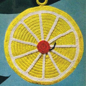 May include: A handmade, crocheted lemon slice potholder with a red cherry center and a black stem. The potholder is yellow with white segments and a loop for hanging. This kitchen item is designed to protect surfaces from heat.