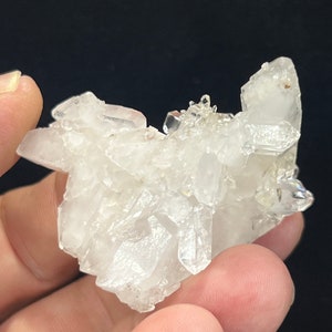 May include: A cluster of clear quartz crystals with a variety of shapes and sizes. The crystals are clustered together in a natural formation, creating a unique and beautiful display.