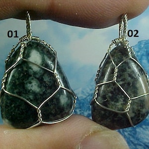 May include: Two green and white stone pendants with silver wire cages. The pendants are labeled "01" and "02".