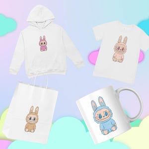 Puede incluir: Una colecci&oacute;n de productos con un dise&ntilde;o de conejo de dibujos animados. Incluye una sudadera con capucha blanca, una camiseta blanca, una bolsa de papel blanca y una taza blanca. El conejo tiene un dise&ntilde;o &uacute;nico con una cara sonriente y en diferentes colores.