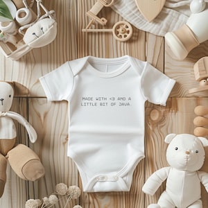 May include: White baby onesie with the text "MADE WITH <3 AND A LITTLE BIT OF JAVA." surrounded by baby toys. The onesie is short-sleeved and has snaps at the bottom. The toys include a stuffed bear, a stuffed dog, and wooden toys.