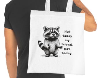 Könnte beinhalten: Weiße Tragetasche mit einer Schwarz-Weiß-Illustration eines Waschbären und dem Text "Not today my friend, not today." Der Waschbär ist mit ausgestreckten Armen dargestellt. Die Tasche hat weiße Griffe.