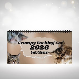Può includere: Un calendario da scrivania per il 2026 con rilegatura a spirale, con tre facce di gatto. Il testo "Grumpy Fucking Cat 2026 Desk Calendar" è stampato sulla parte anteriore.