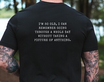 Op de afbeelding: Zwart t-shirt met witte tekst: "I'M SO OLD, I CAN REMEMBER GOING THROUGH A WHOLE DAY WITHOUT TAKING A PICTURE OF ANYTHING." Het shirt is gemaakt van zacht materiaal en is geschikt voor casual wear.