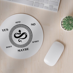 Könnte beinhalten: Eine weiße runde Mausmatte mit einem schwarzen Schlangenmuster in der Mitte. Die Schlange ist von einem schwarz-weißen griechischen Schlüsselmuster umgeben. Die Wörter "YES", "NO", "MAYBE", "MIND", "BODY" und "SPIRIT" stehen um die Schlange herum.