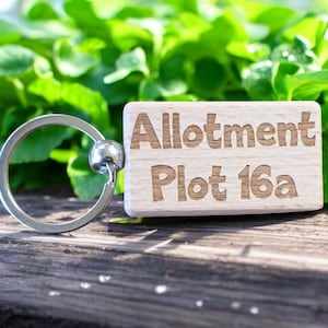 May include: A wooden keyring with a silver ring. The keyring has the text "Allotment Plot 16a" engraved on it.