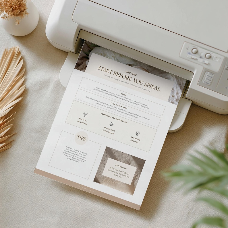 Op de afbeelding: Een witte printer die een beige en wit document afdrukt. Het document bevat de tekst "START BEFORE YOU SPIRAL" en bevat secties voor lessen, actiestappen en tips. De printer staat op een wit oppervlak.