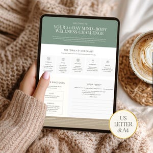 May include: A digital tablet displays a 21-day mind-body wellness challenge. The screen features text, checklists, and sections for daily goals. A cup of coffee sits beside the tablet. The tablet is held by a person wearing a beige sweater.
