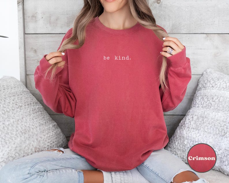 May include: A crimson red sweatshirt with the text "be kind." in white lettering.