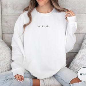 May include: White sweatshirt with the text "be kind." printed on the front.