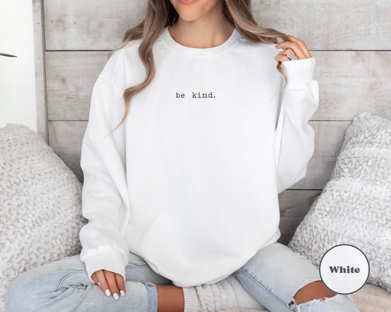 May include: White sweatshirt with the text "be kind." printed on the front.