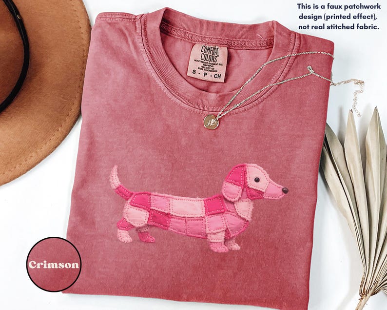 May include: Crimson-colored t-shirt featuring a patchwork dachshund design. The shirt has a crew neck and short sleeves. The text on the shirt reads "COMFORT COLORS" and "S-P-CH". The image also includes the text "This is a faux patchwork design (printed effect), not real stitched fabric."