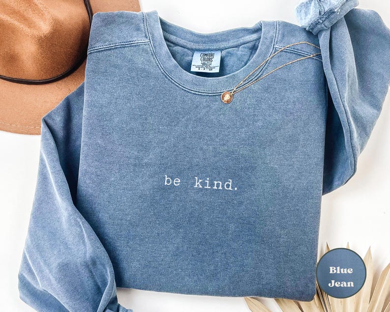 May include: A blue jean sweatshirt with the text "be kind." embroidered on the front.