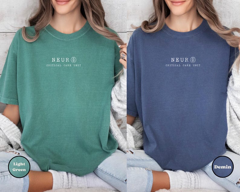 May include: Two short-sleeved t-shirts, one light green and one denim blue. Each shirt has the word "NEUR" above "CRITICAL CARE UNIT" in white text. The shirts are worn with light-wash jeans.