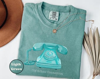 May include: A light green t-shirt with a vintage turquoise rotary phone graphic and the text "Old School Connection".