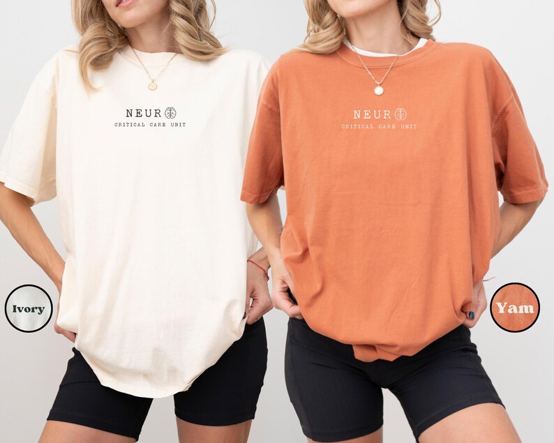 May include: Two oversized t-shirts, one ivory and one yam-colored, each featuring the text "NEUR CRITICAL CARE UNIT" in black. The shirts are paired with black shorts. The ivory shirt is labeled "Ivory" and the yam shirt is labeled "Yam".