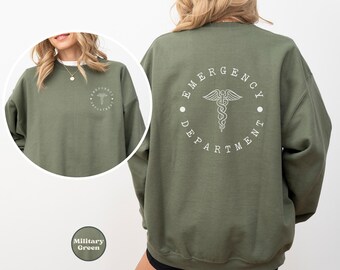 May include: Olive green sweatshirt with white "Emergency Department" text and medical symbol on the back. The front features a smaller matching design. The sweatshirt is a solid color and has a crew neck.