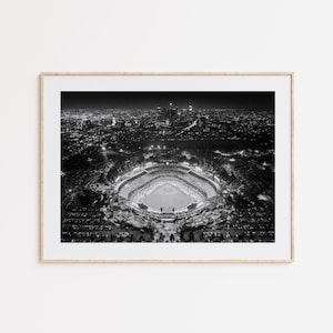 May include: A black and white aerial photograph of a baseball stadium at night, with the city lights in the background.