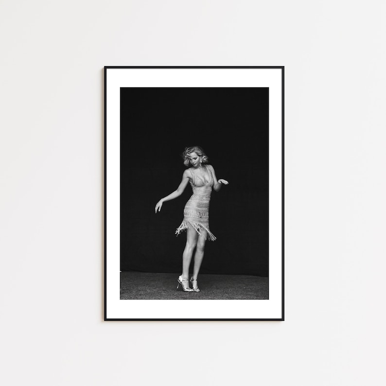 May include: A black and white photograph of a woman wearing a sequined dress and posing in a studio setting.