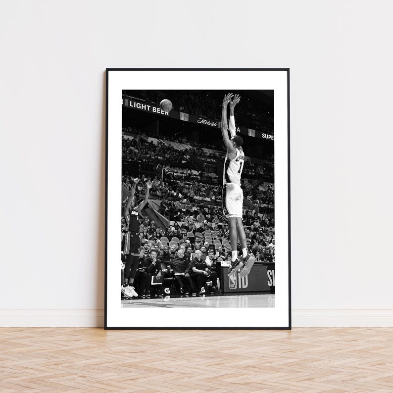 May include: Black and white framed print of a basketball player mid-air, shooting a ball. The player is wearing a jersey with the number 7. The background shows a crowd of spectators and the words "LIGHT BEER" and "SUPER".