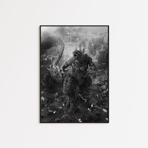 May include: Black and white framed print of Godzilla, a giant monster, destroying a city. The artwork depicts Godzilla roaring amidst the rubble of buildings, with smoke and debris filling the air. The print is mounted in a black frame.