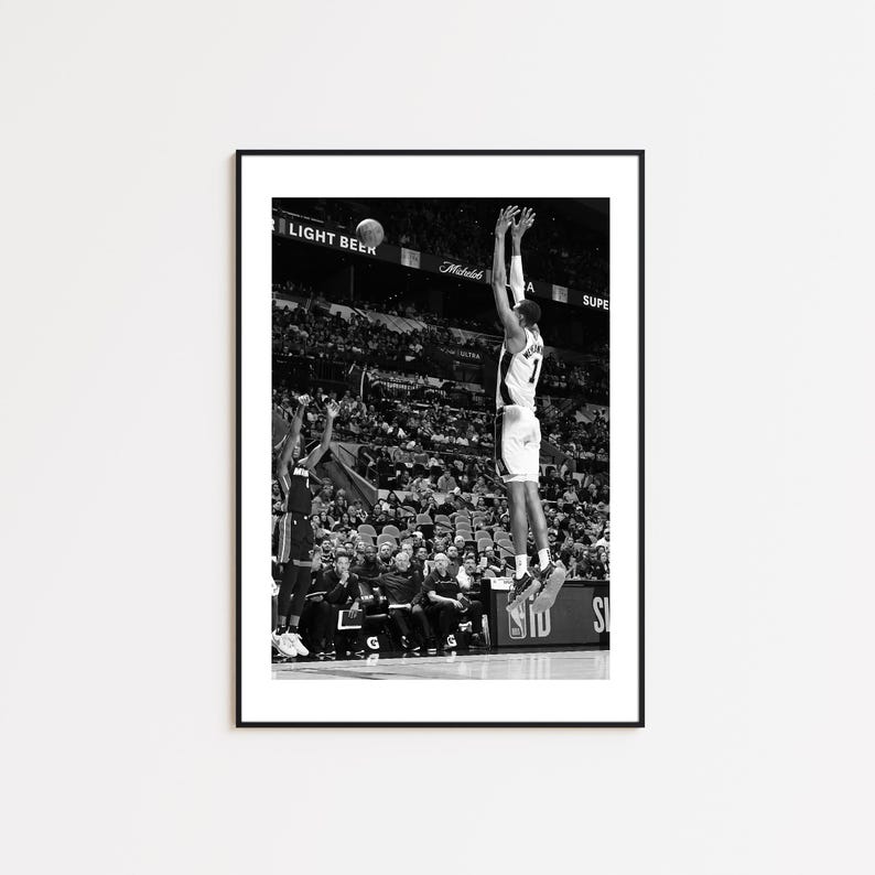 May include: Black and white framed print of a basketball player mid-air, shooting a ball. The player is wearing a jersey with the number 7. The background shows a crowd of spectators and the words "LIGHT BEER".
