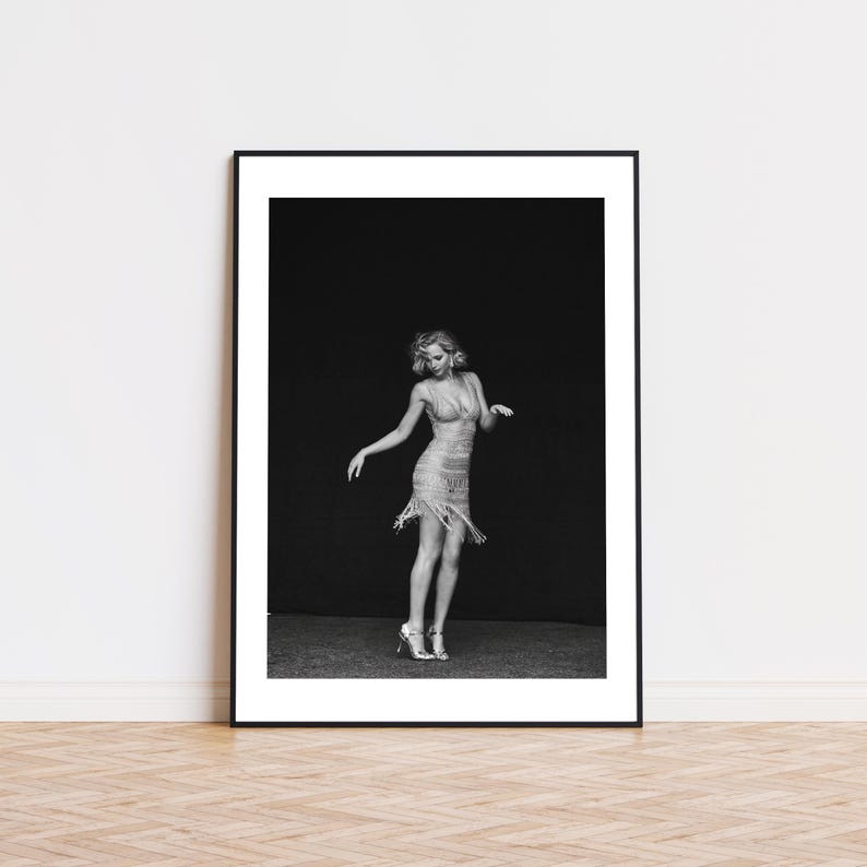 May include: A black and white photograph of a woman wearing a sequined dress and heels, posing against a dark backdrop.