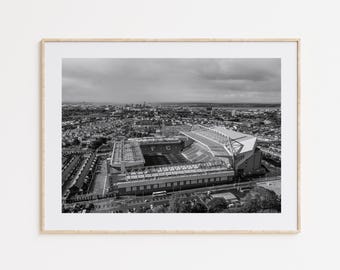 May include: Black and white aerial photograph of a large stadium with the letters "F.C." visible on the field. The stadium is surrounded by a city with houses and buildings.