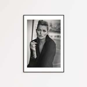 Può includere: Stampa incorniciata in bianco e nero con un ritratto di una persona che tiene una sigaretta. La persona indossa una camicia nera. L'immagine è un primo piano con uno sfondo sfocato.