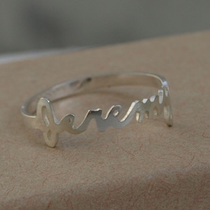 May include: A silver ring with the word "forever" inscribed in cursive lettering.