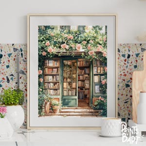 Puede incluir: Impresión en acuarela enmarcada de la entrada de una librería. La puerta verde está abierta, revelando estanterías llenas de libros. Rosas rosas y follaje verde adornan la parte superior de la puerta y el marco. La imagen está etiquetada como "Prints by Bapt".