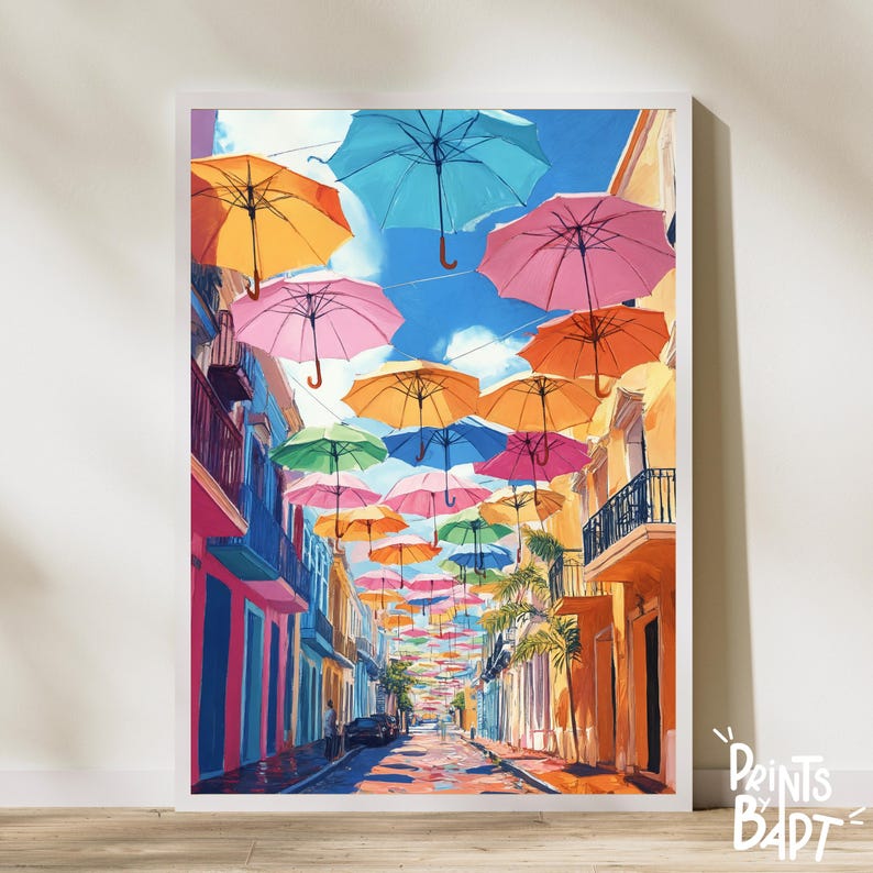 May include: A colourful street scene with a row of buildings and a street lined with colourful umbrellas hanging overhead. The umbrellas are in various shades of pink, blue, yellow, orange, and green.