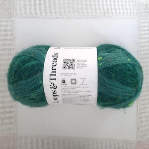 May include: A ball of Loops & Threads yarn in a deep teal color with flecks of yellow and green. The label includes the text "Adventure/Aventurine" and details about the yarn's composition and needle size.
