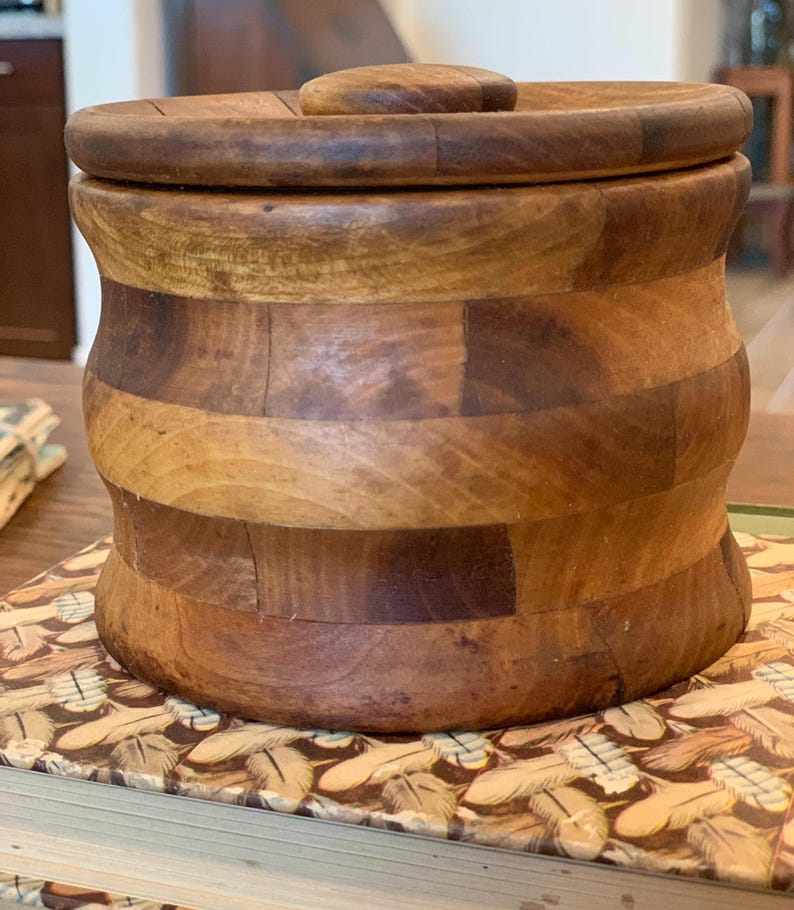 Op de afbeelding: Een houten container met een deksel, gemaakt van meerdere stukken hout, met een natuurlijke houten afwerking.
