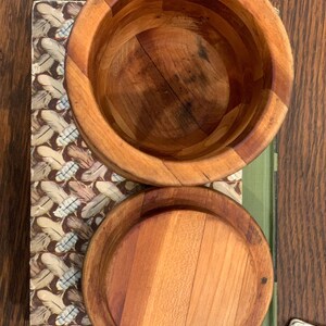 Op de afbeelding: Twee houten kommen met deksels. De kommen zijn gemaakt van lichtbruin hout en hebben een natuurlijke afwerking. De deksels zijn ook van hout en hebben een glad oppervlak.