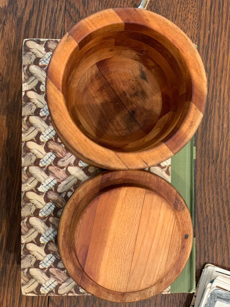 Op de afbeelding: Twee houten kommen met deksels. De kommen zijn gemaakt van lichtbruin hout en hebben een natuurlijke afwerking. De deksels zijn ook van hout en hebben een glad oppervlak.