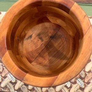 Op de afbeelding: Een houten kom met een natuurlijke afwerking. De kom is gemaakt van meerdere stukken hout die aan elkaar zijn gelijmd. De kom is leeg en klaar voor gebruik.