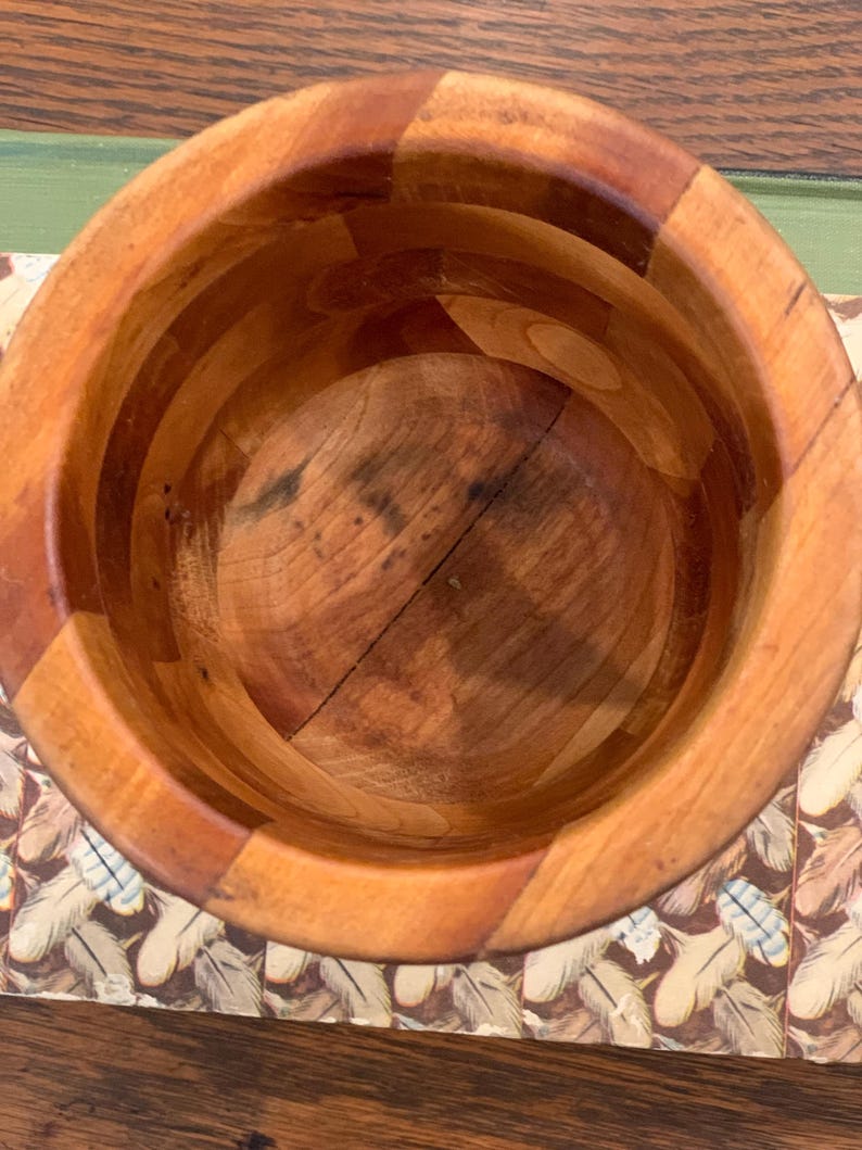 Op de afbeelding: Een houten kom met een natuurlijke afwerking. De kom is gemaakt van meerdere stukken hout die aan elkaar zijn gelijmd. De kom is leeg en klaar voor gebruik.