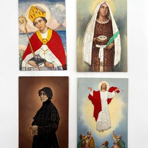 May include: Four rectangular religious prayer cards featuring illustrations. Top left: a bishop in red robes with a gold miter. Top right: a figure in a brown patterned dress holding a plate with eyes. Bottom left: a figure in black lace labeled Venerable Mother Seton. Bottom right: a robed figure ascending above a group of people.