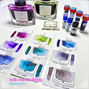 May include: An assortment of colorful fountain pen inks and ink swatches. The image features bottles of ink, ink samples, and the text "ink swatching". The ink colors include purple, green, blue, and brown.