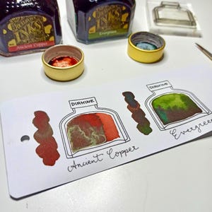May include: Image of Diamine our ink bottle stamps can be matched to your favourite fountain pen ink brands. The image shows ink bottles, ink samples swatched onto ink swatch cards. The ink samples show the colour variations of the inks.